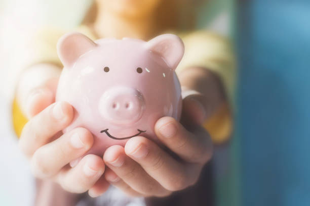 A person holding a pink piggy bank with a smiling face.